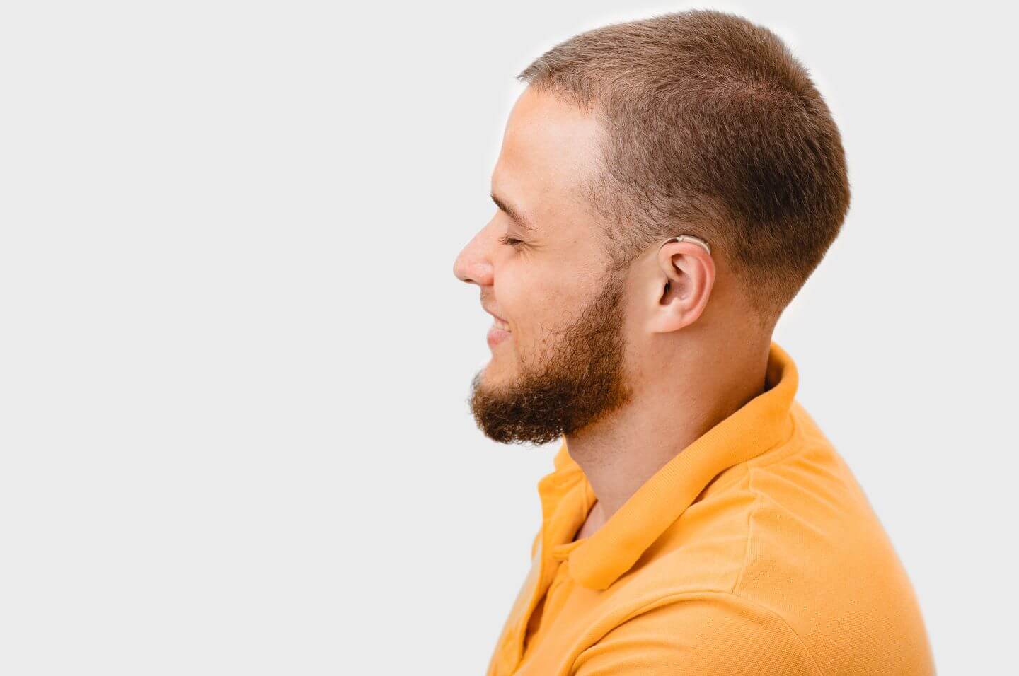 Side view of smiling man with hearing aid