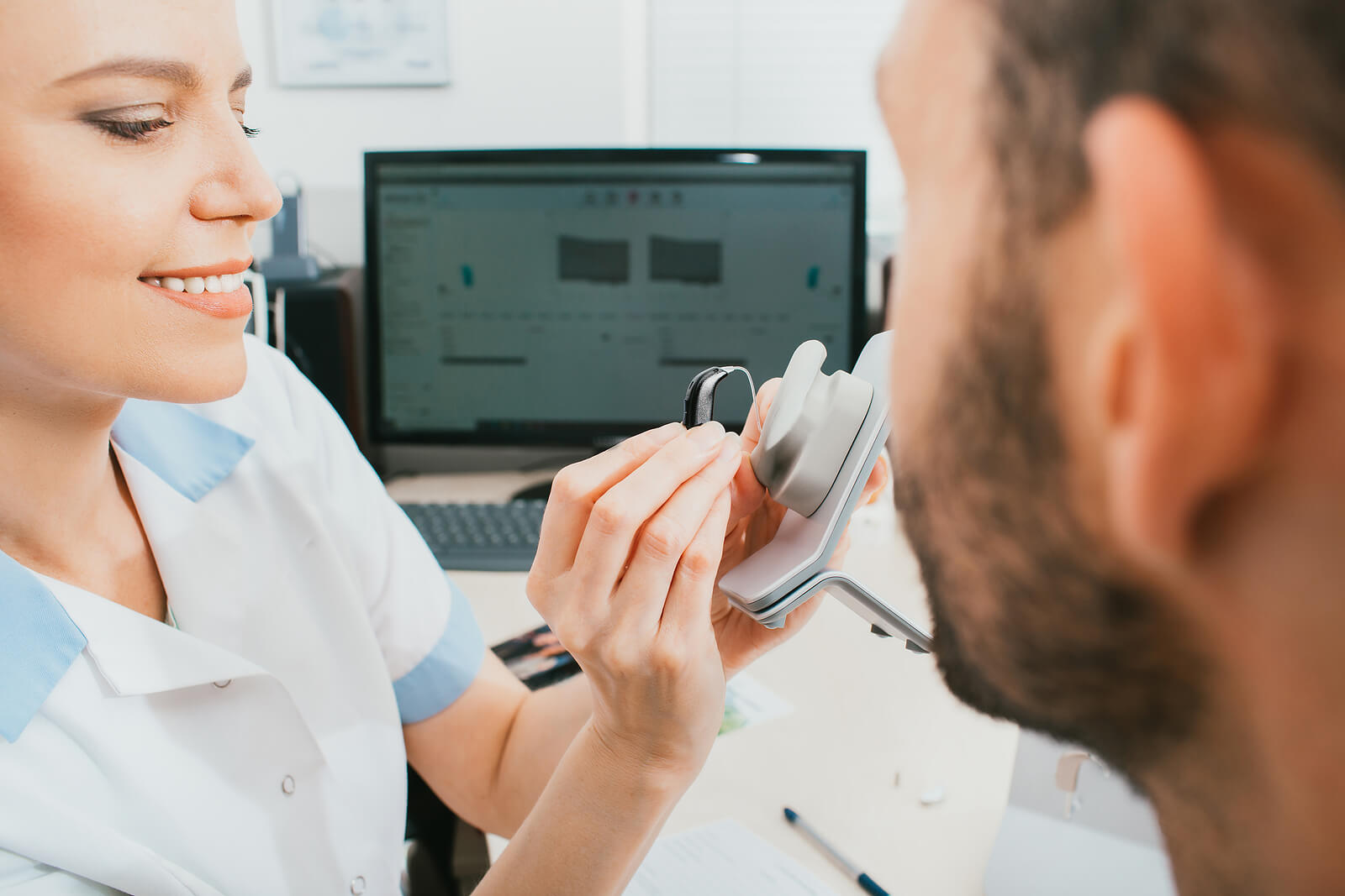 Hearing Instrument Specialist showing patient a hearing aid